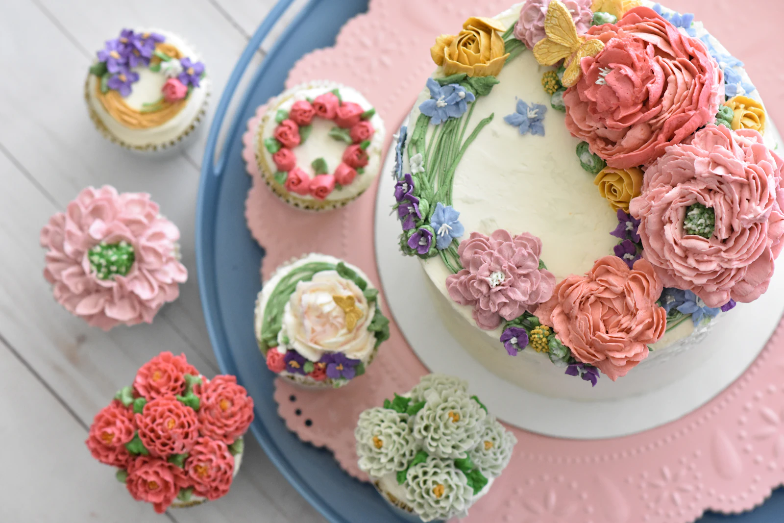 Zweistöckige Torte mit glatter Buttercreme, dunklem Schokoladen-Drip, frischen Himbeeren und essbaren Hornveilchen