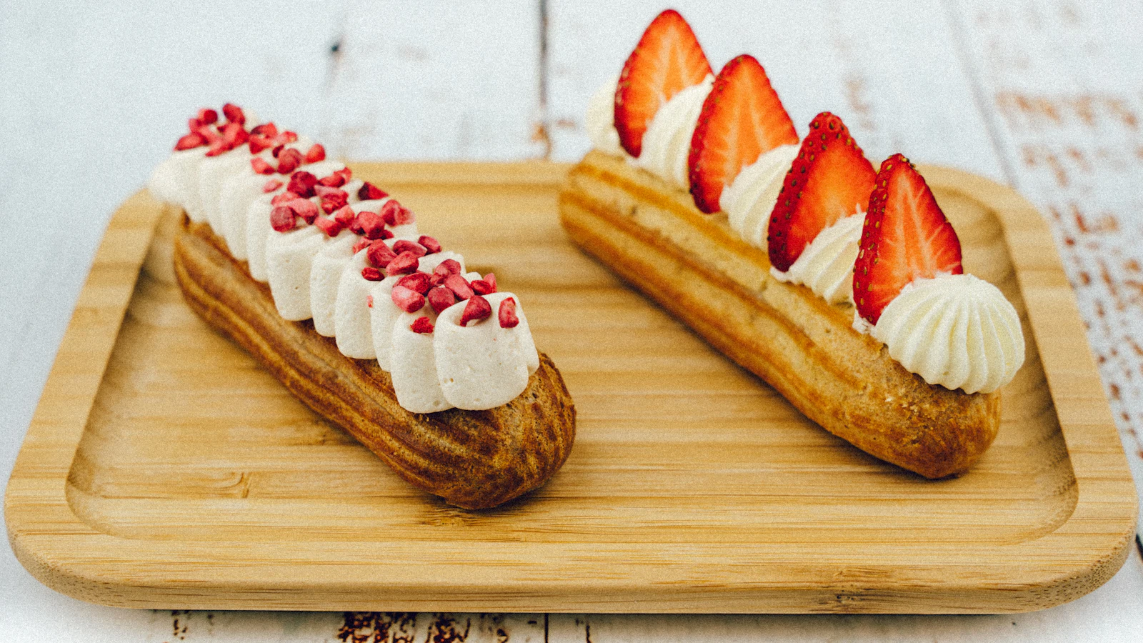 Schokoladen-Éclairs, bunte Macarons und eine gestürzte Tarte Tatin mit glänzendem Karamell auf einer Marmorplatte