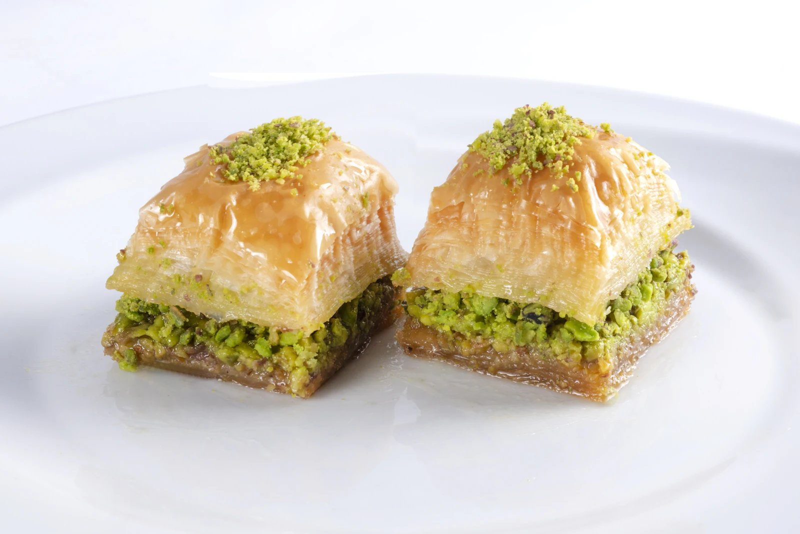 Holztisch mit Baklava-Rauten, goldenen Pastéis de Nata, bunten Mochi-Kugeln und gefüllten Cannoli auf verschiedenen Tellern