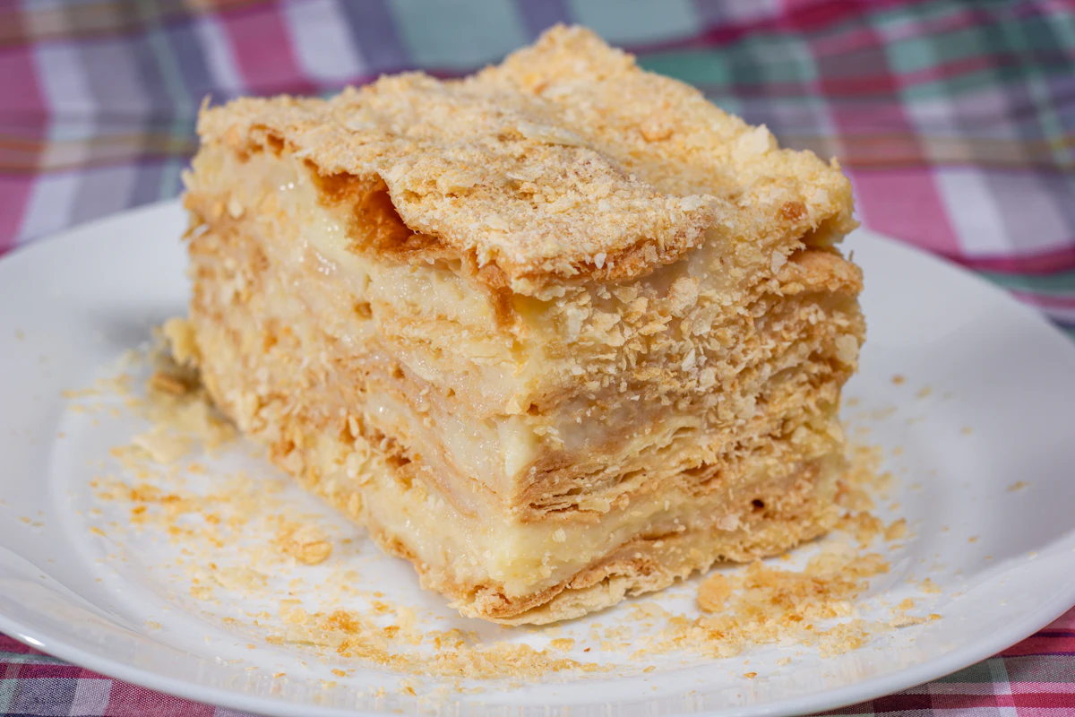 Hoher Quark-Käsekuchen mit goldbrauner Oberfläche, daneben eine Schüssel abgetropfter Quark
