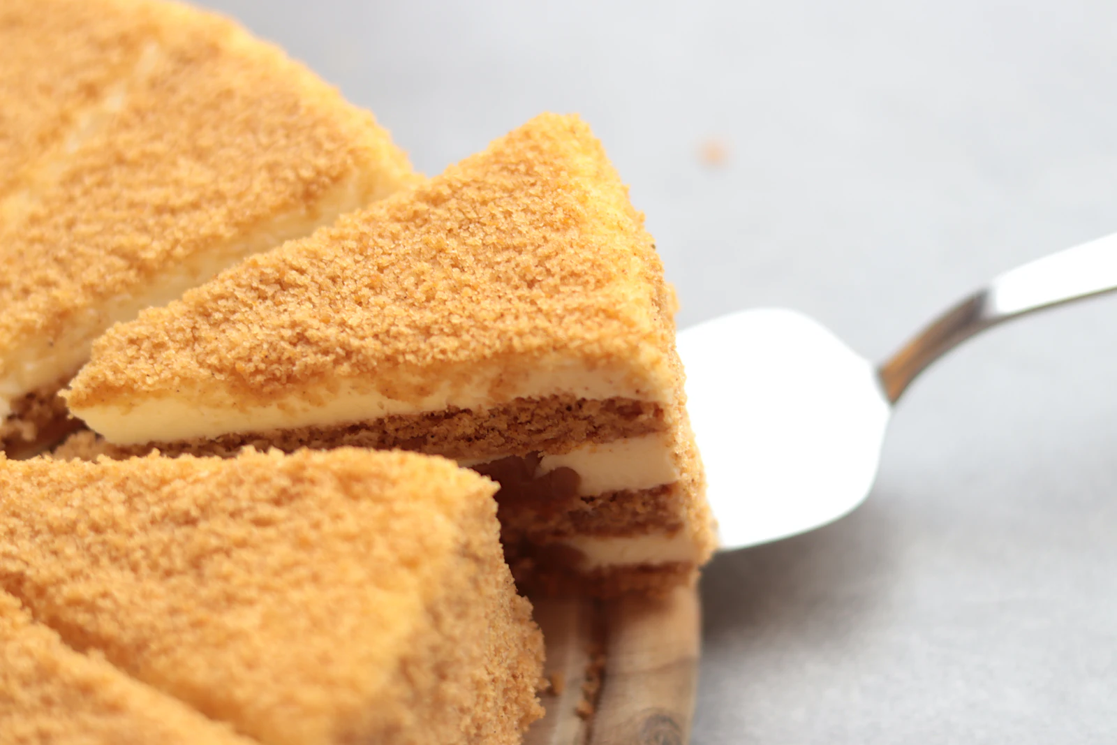 Angeschnittene Honigtorte mit vielen dünnen Schichten und heller Schmandcreme auf einem Holzbrett